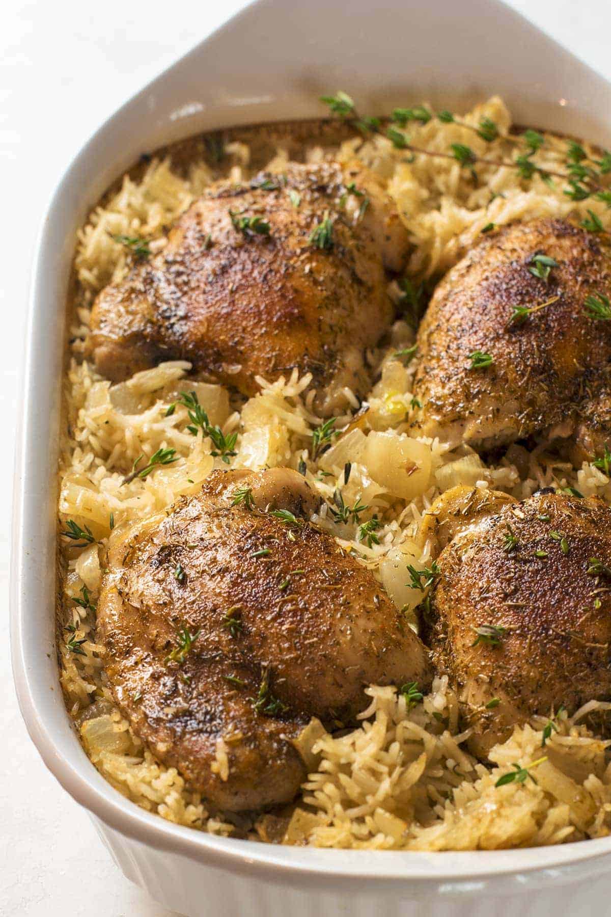 Oven baked chicken and rice in white baking dish.