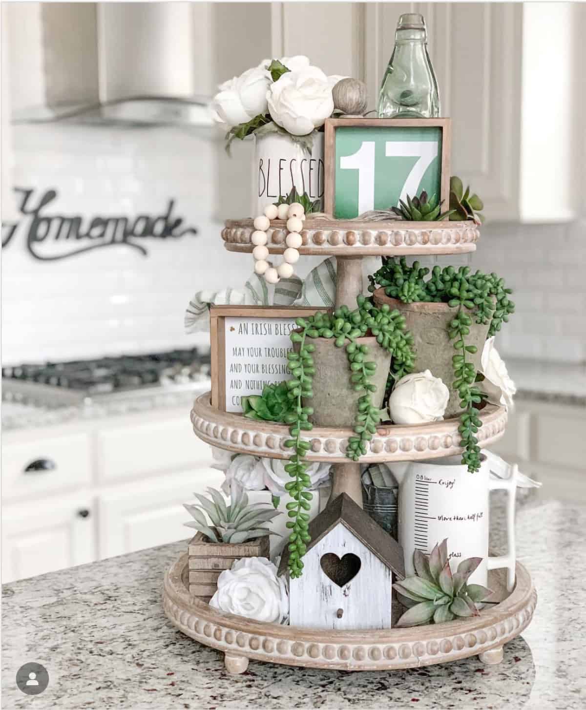 3-tiered wood tray with white and gray decorations and succulents on marble countertop. 
