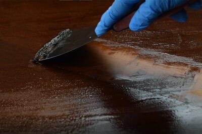 Stripping furniture stain with a chemical stripper.