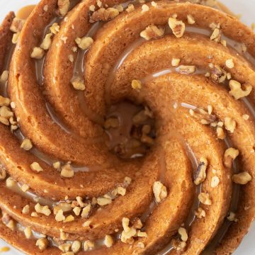 Aerial view of Bailey's Irish creme cake in a Beautiful bundt swirl pattern, topped with Bailey's caramel glaze and chopped walnut pieces.