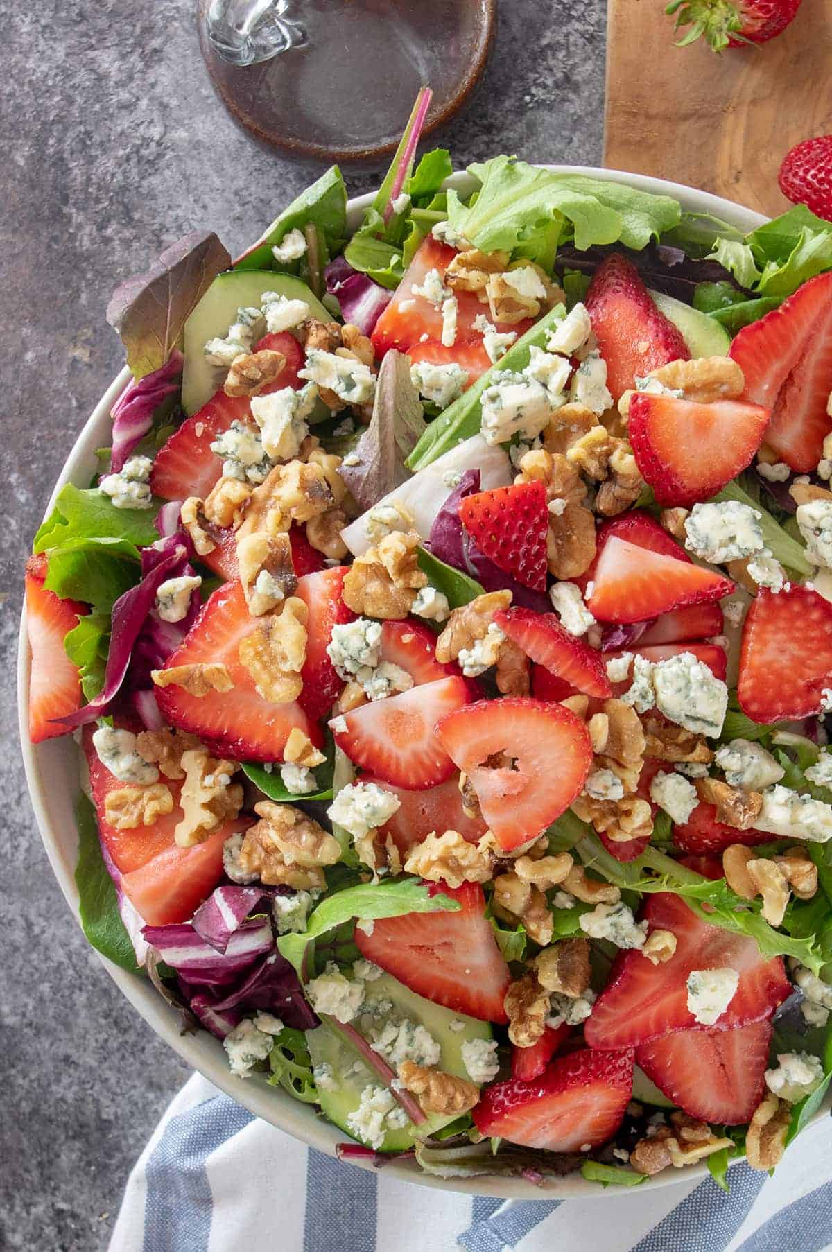 Overhead of Strawberry Spinach Salad with Raspberry Vinaigrette Dressing to show texture of toppings.