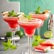 Three frozen Watermelon Margaritas in glasses with sugar rim.