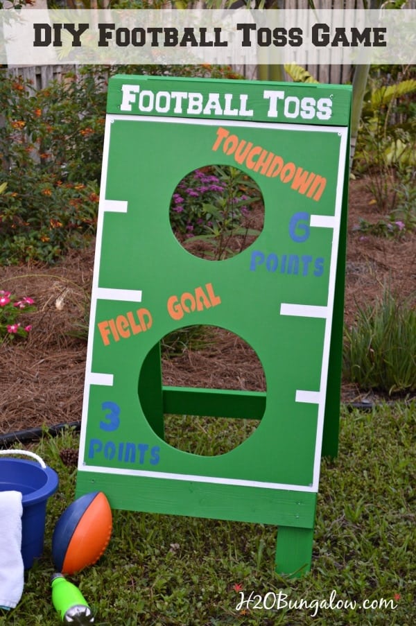 DIY football toss game decorated green with white markings in a flower garden.