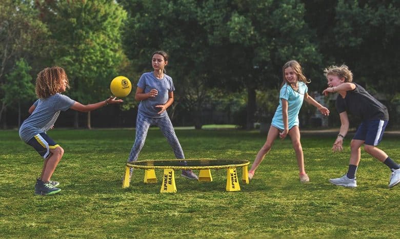 Children playing spikeball around a trampoline.