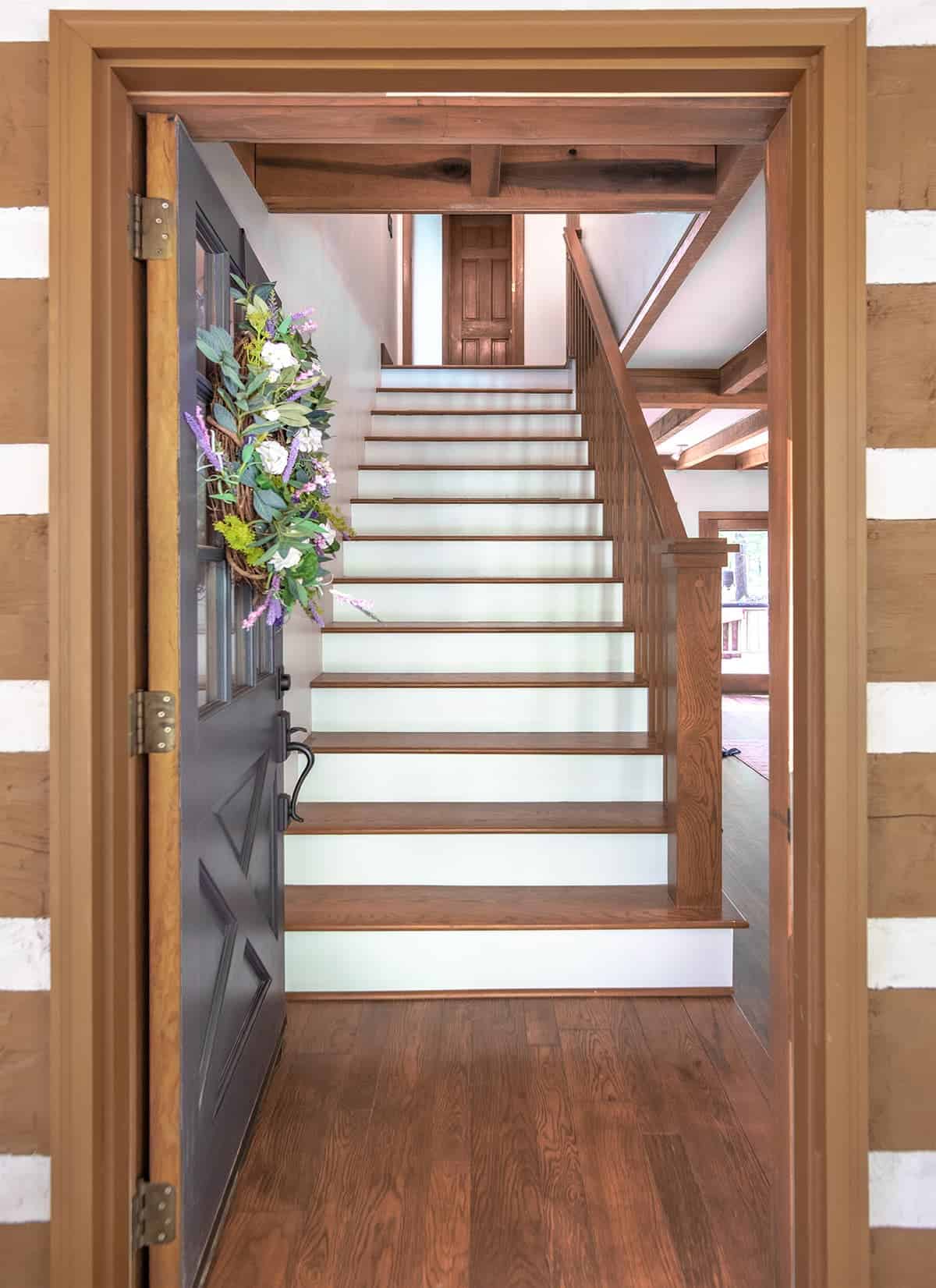 View of rustic modern white and wood staircase through an open door.