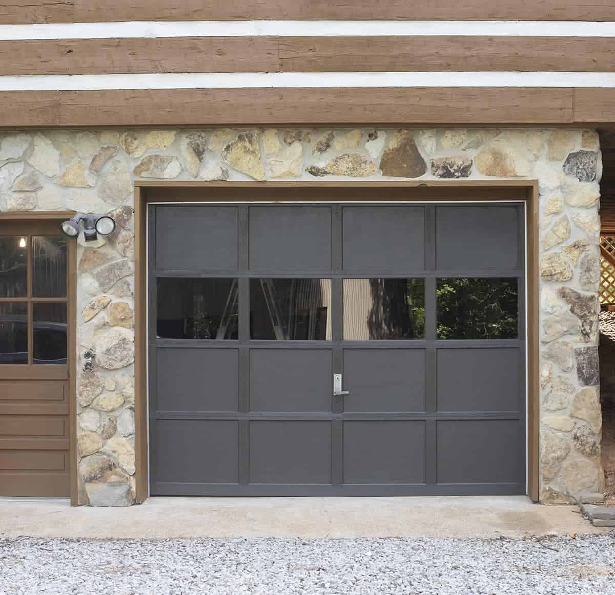 Black painted wooden garage door against stone exterior.