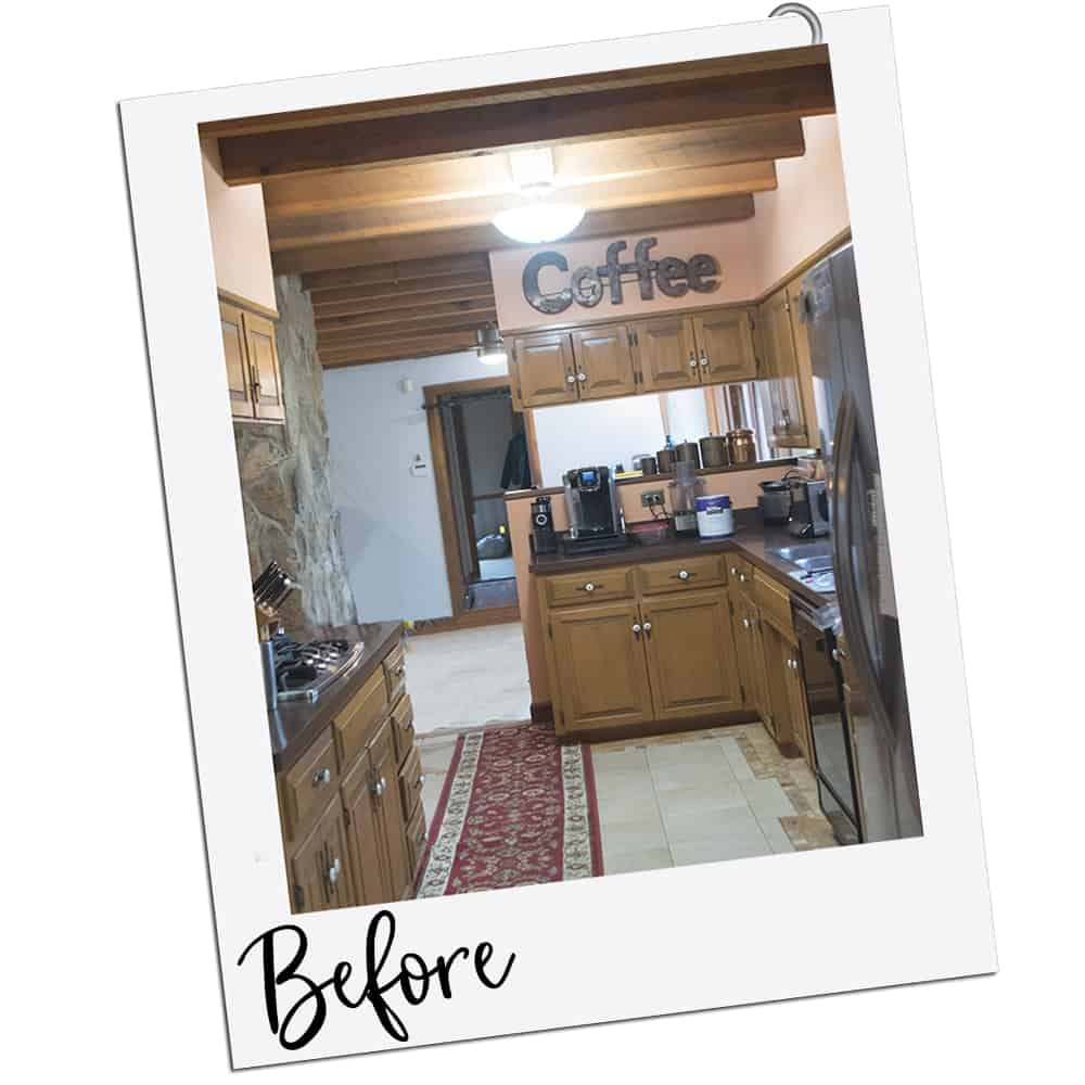 A dated kitchen with peach walls and wood cabinets with travertine floor.