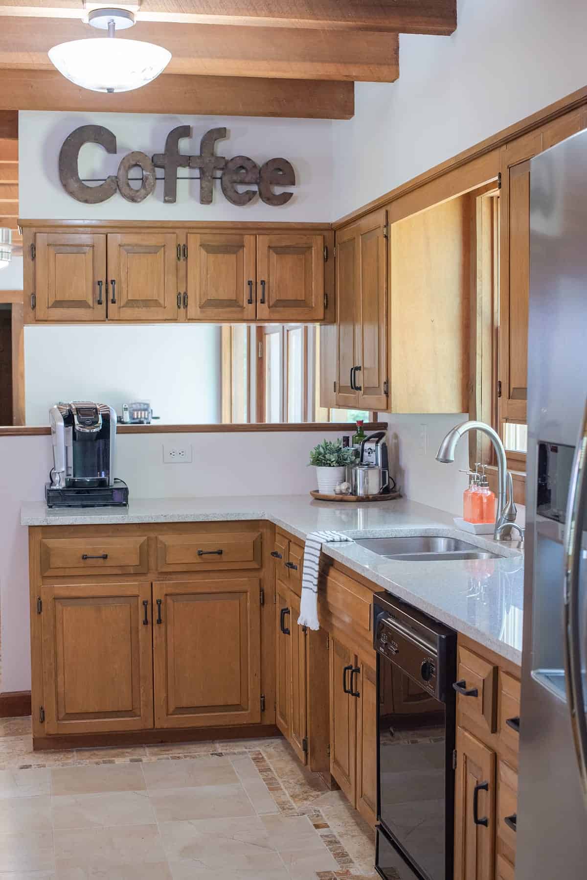 Kitchen with wood cabinets and white walls with a coffee station in view.