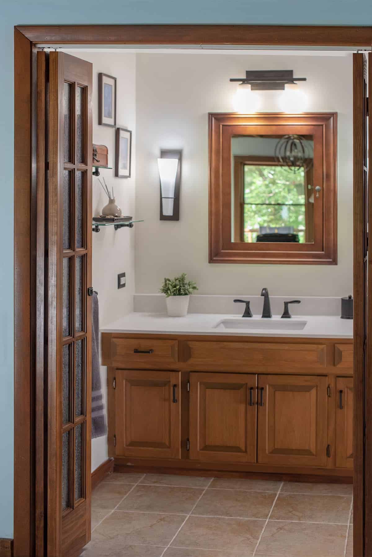 Rustic bathroom with beige walls, wood vanity, mirror and doors.