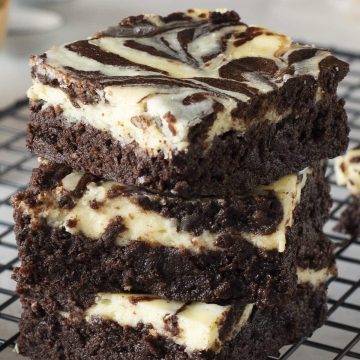 Cheesecake Brownies stacked 3 high on top of a cooking cooling rack.