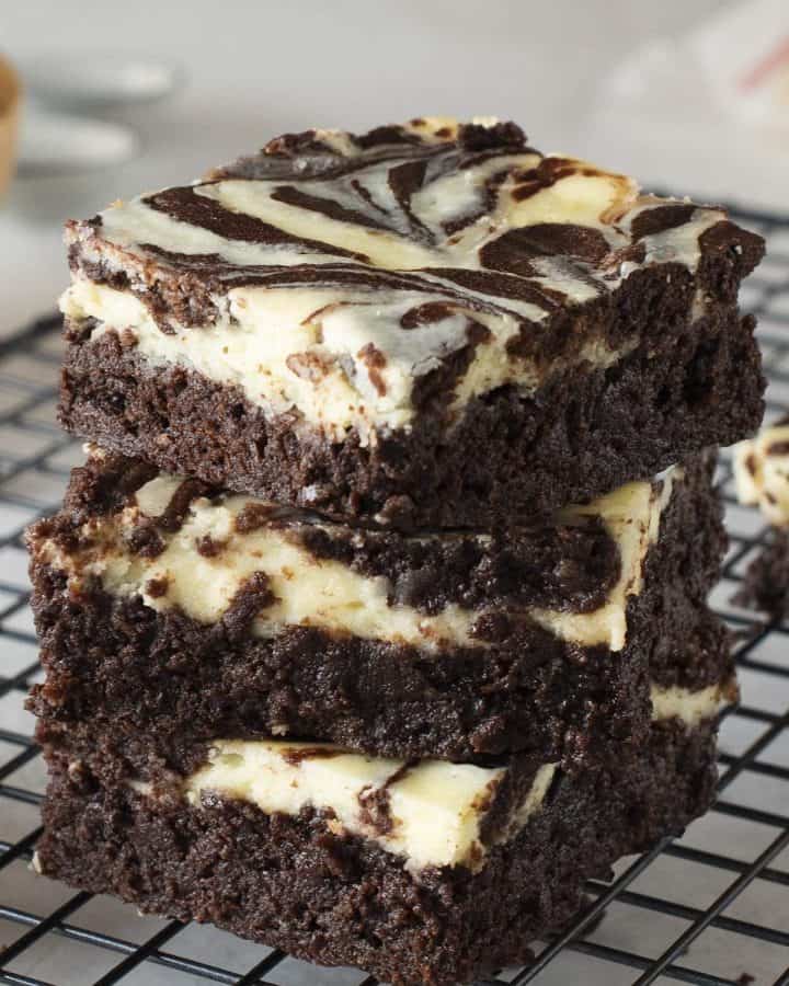 Cheesecake Brownies stacked 3 high on top of a cooking cooling rack.