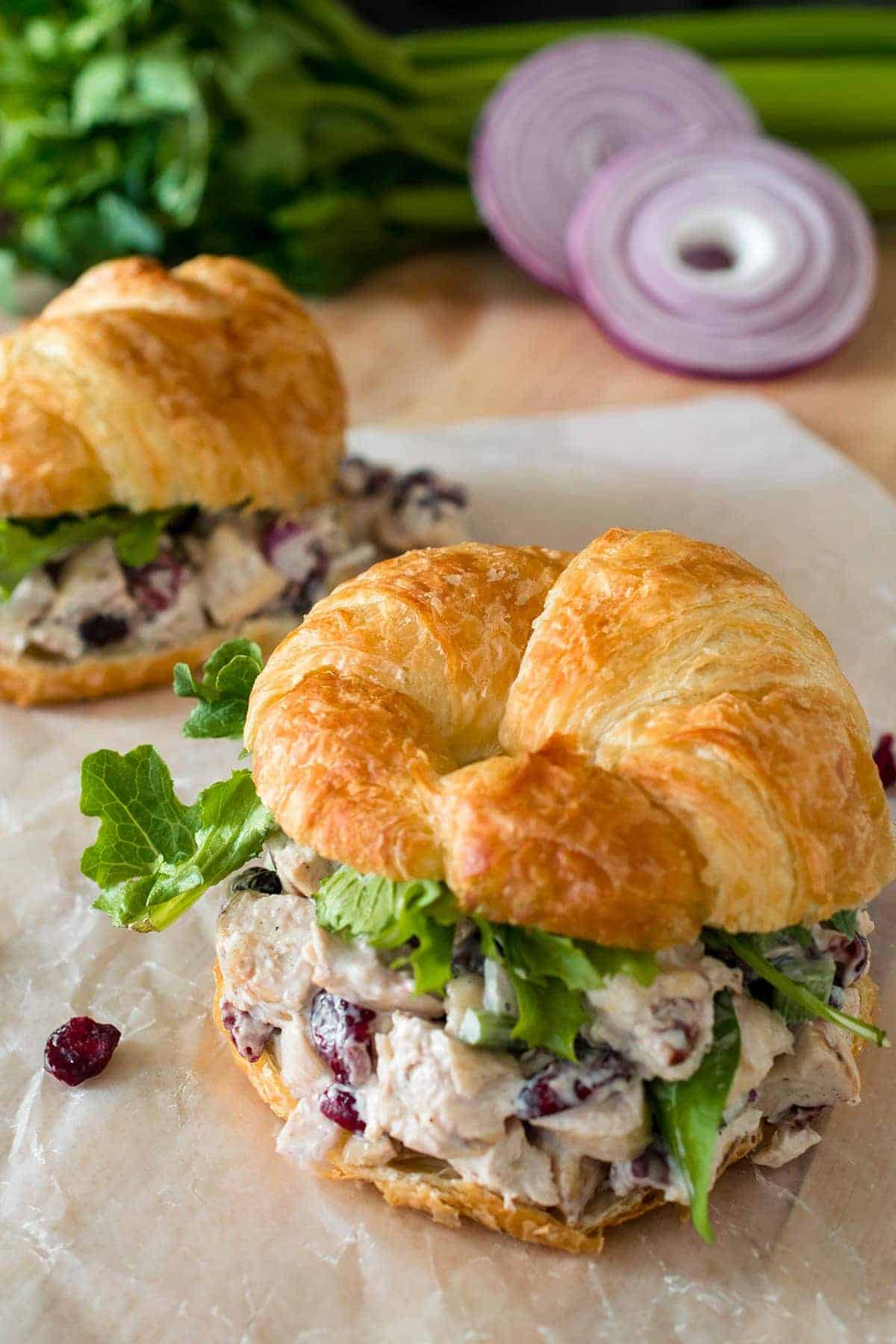 Cranberry Chicken Salad on a Croissant with arugula lettuce on wax paper.