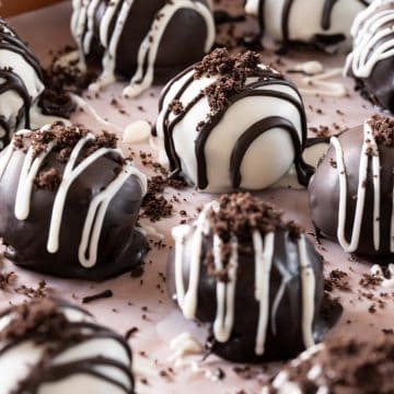 Oreo Balls on a cookie sheet. Cookies are drizzled with white and dark chocolate.