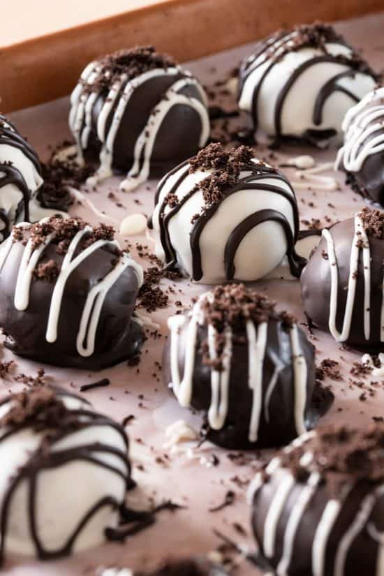 Oreo Balls on a cookie sheet. Cookies are drizzled with white and dark chocolate.