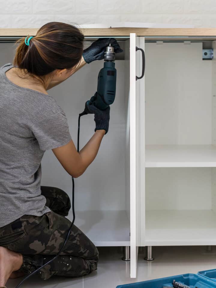 Woman removing old countertops with a drill.