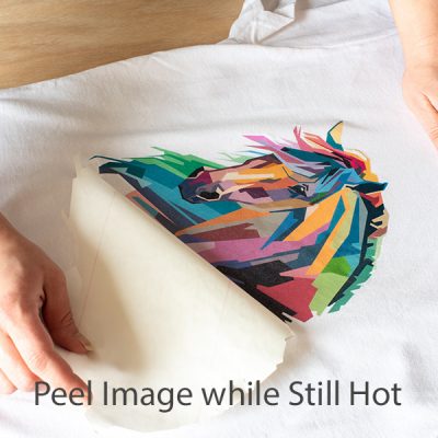 A woman peeling back transfer paper from a t-shirt.