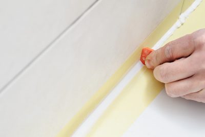 A caulk smoother tool being used to smooth out caulk on a bathtub.