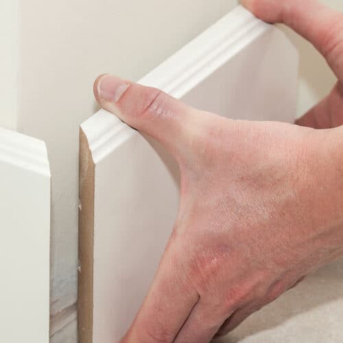 Man holding up baseboards for a corner.