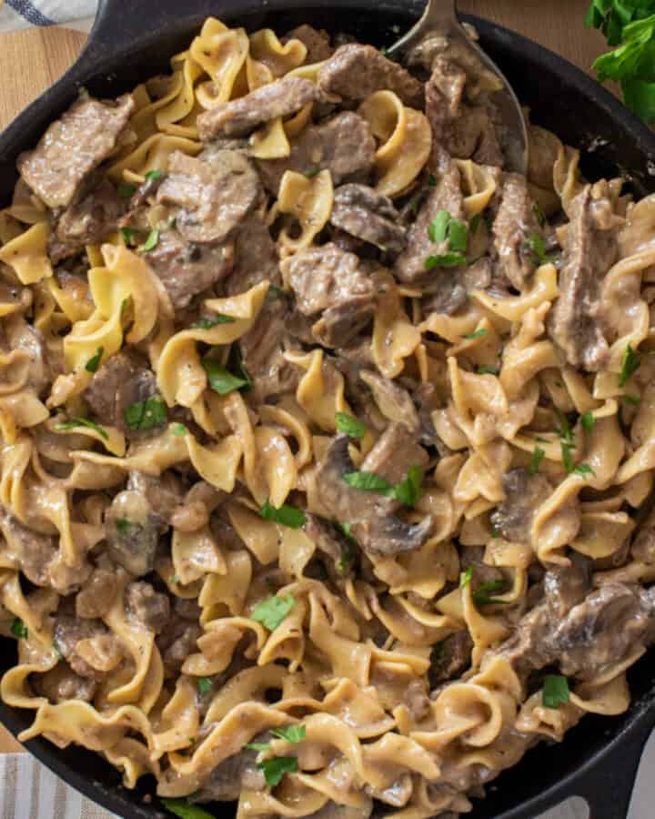 Top down view of beef stroganoff with noodles in a skillet.