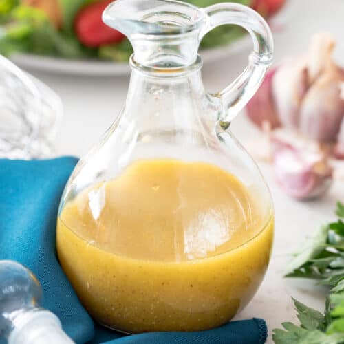 Cruet Bottle of White Balsamic Salad Dressing with ingredients scattered around.