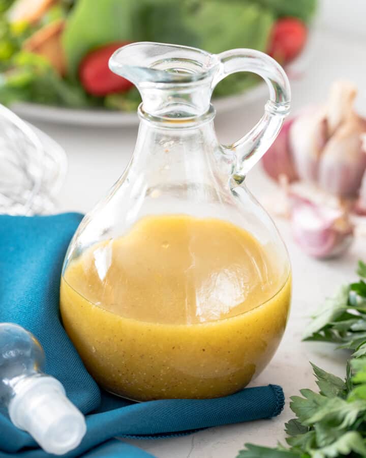 Cruet Bottle of White Balsamic Salad Dressing with ingredients scattered around.