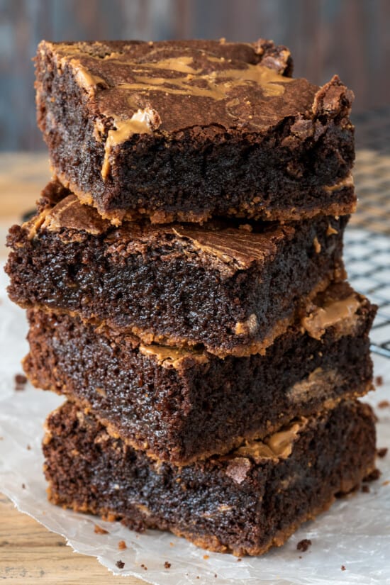 Four Biscoff Brownies stacked high on a wood board.