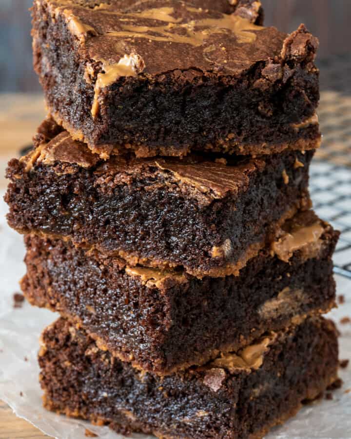 Four Biscoff Brownies stacked high on a wood board.