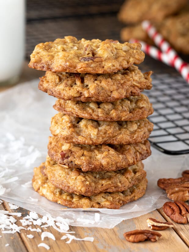 Coconut Pecan Cookies stacked seven high with shredded coconut and whole pecan scattered around.