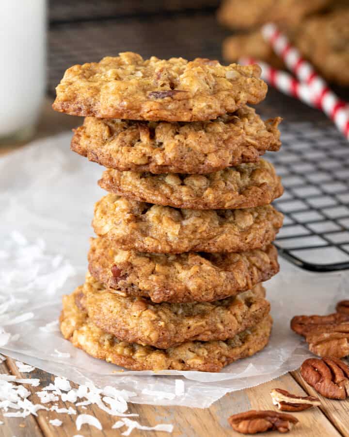 Coconut Pecan Cookies stacked seven high with shredded coconut and whole pecan scattered around.