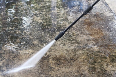 Cleaning concrete with a pressure washer.