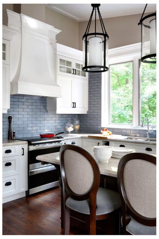 Traditional style kitchen with white cabinets, smoky blue tile backsplash, dark wood floor, and dining table.