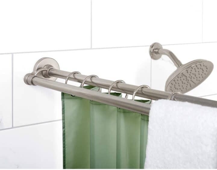 Double curtain rod hung in a shower with towel hung over the side.