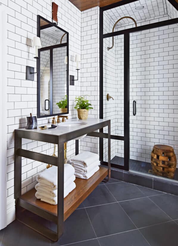 White tiled bathroom with black metal accents and black floor.