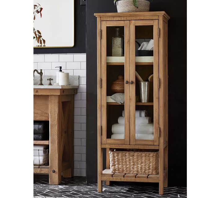 Rustic wood bathroom cabinet with glass doors in a black and white bathroom.