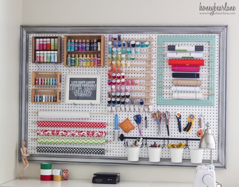 White pegboard on an office wall with craft supplies organized in it.