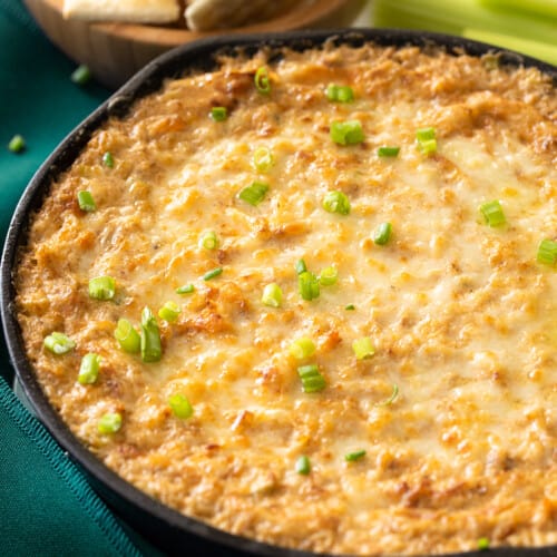 Cheesy Hot Crab Dip in a cast iron pan with crackers on the side.