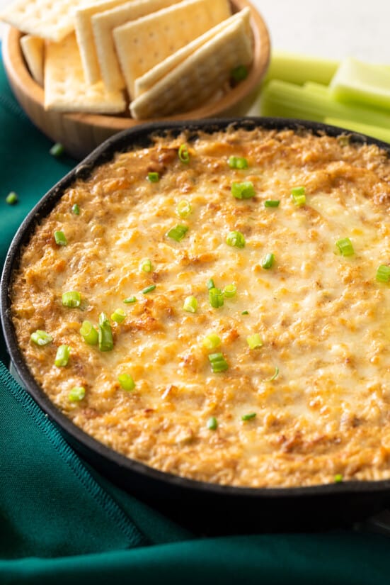 Cheesy Hot Crab Dip in a cast iron pan with crackers on the side.