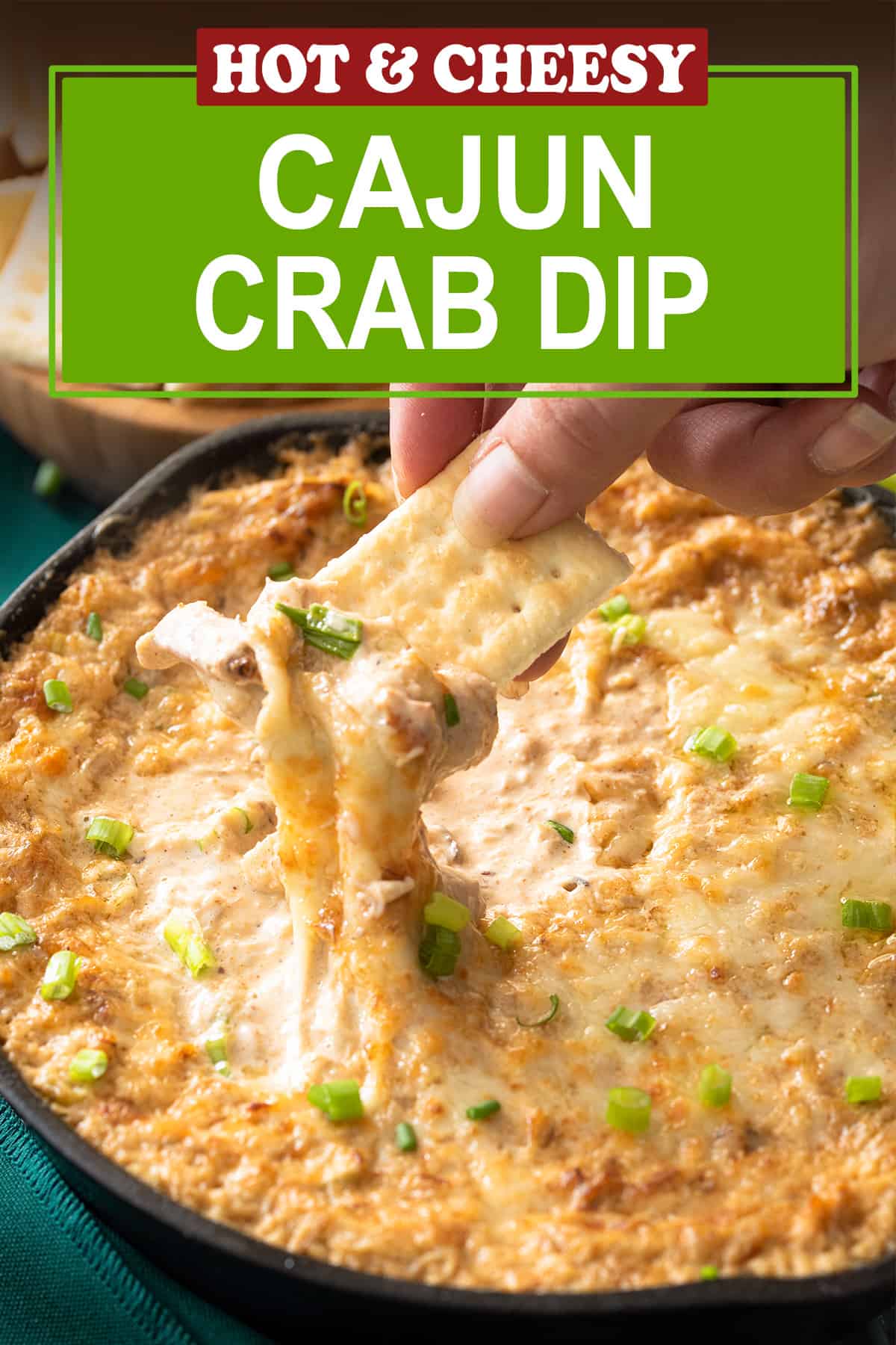 Cracker dipping into Cajun crab dip in a cast iron skillet with post title label.