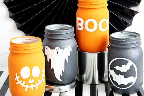 Mason jars painted with spooky characters on them in chalk paint.