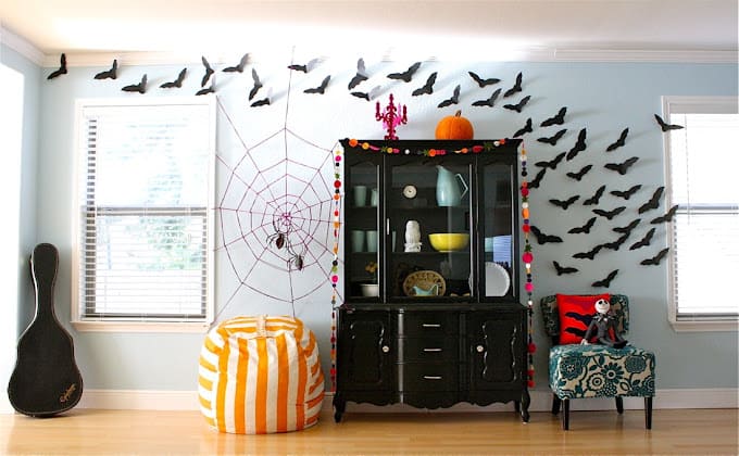 A black hutch with vinyl bats flowing overhead on a white wall and a spider web decoration.