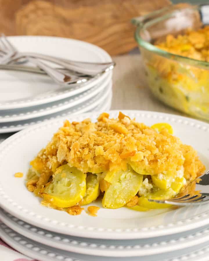 Squash casserole with ritz cracker toping as a side dish served on a stack of plates.