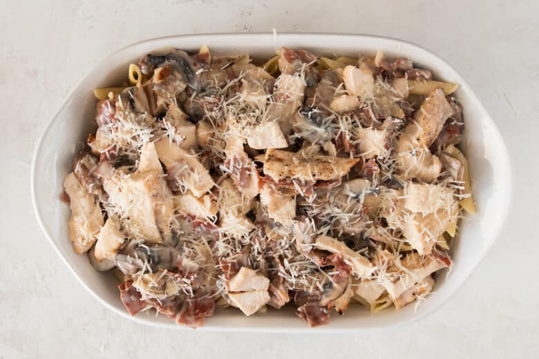 Chicken marsala laid over pasta in a baking dish.