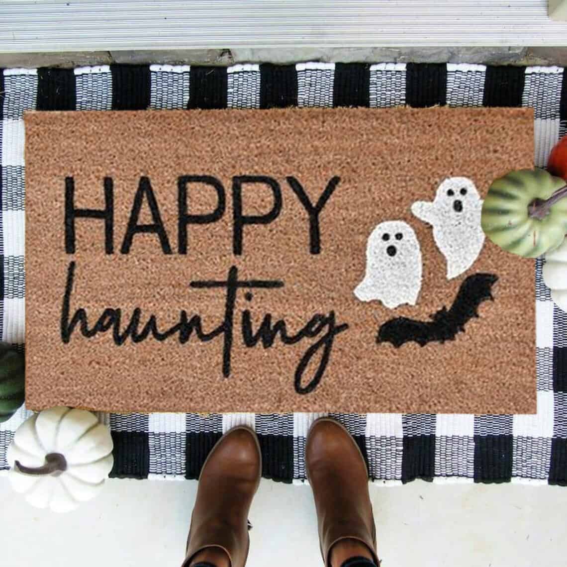 Happy Haunting Halloween doormat in front of door with buffalo check rug underneath.