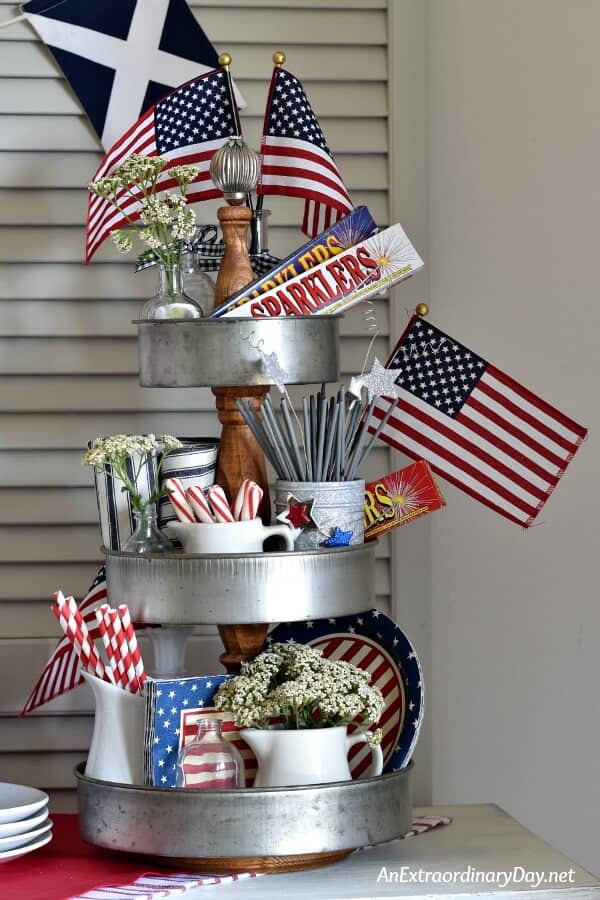 3-tiered galvanized tray styled for 4th of July party. Patriotic plates, napkins and straws mixed with candies, fresh flowers and other accents