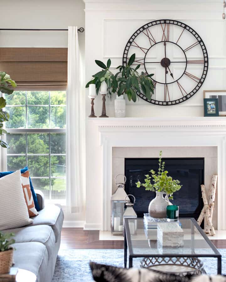 Neutral living room design with cream mantel, glass table, and green accents colors.