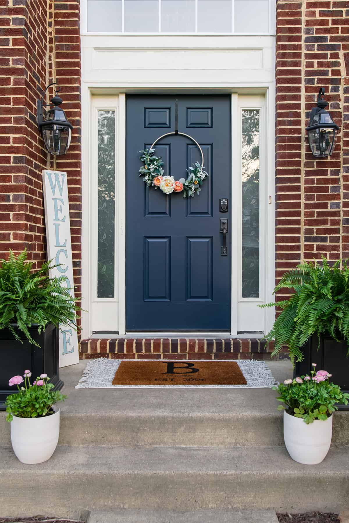 Dark blue font door on a brick house stoop with planters.