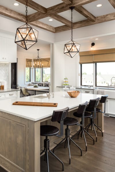 Kitchen island with lights over it with gray brown wood ceilings and floors.