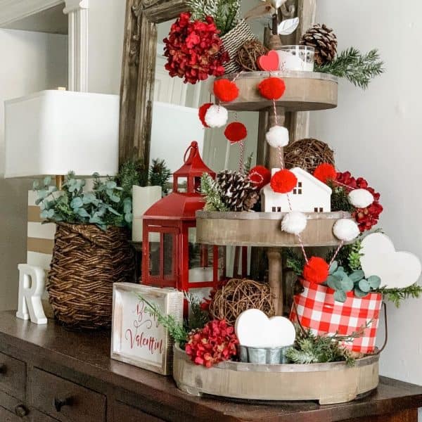 3-tiered wooden rustic tray with pine cones, winter greenery and red & white Valentine's Day accents.