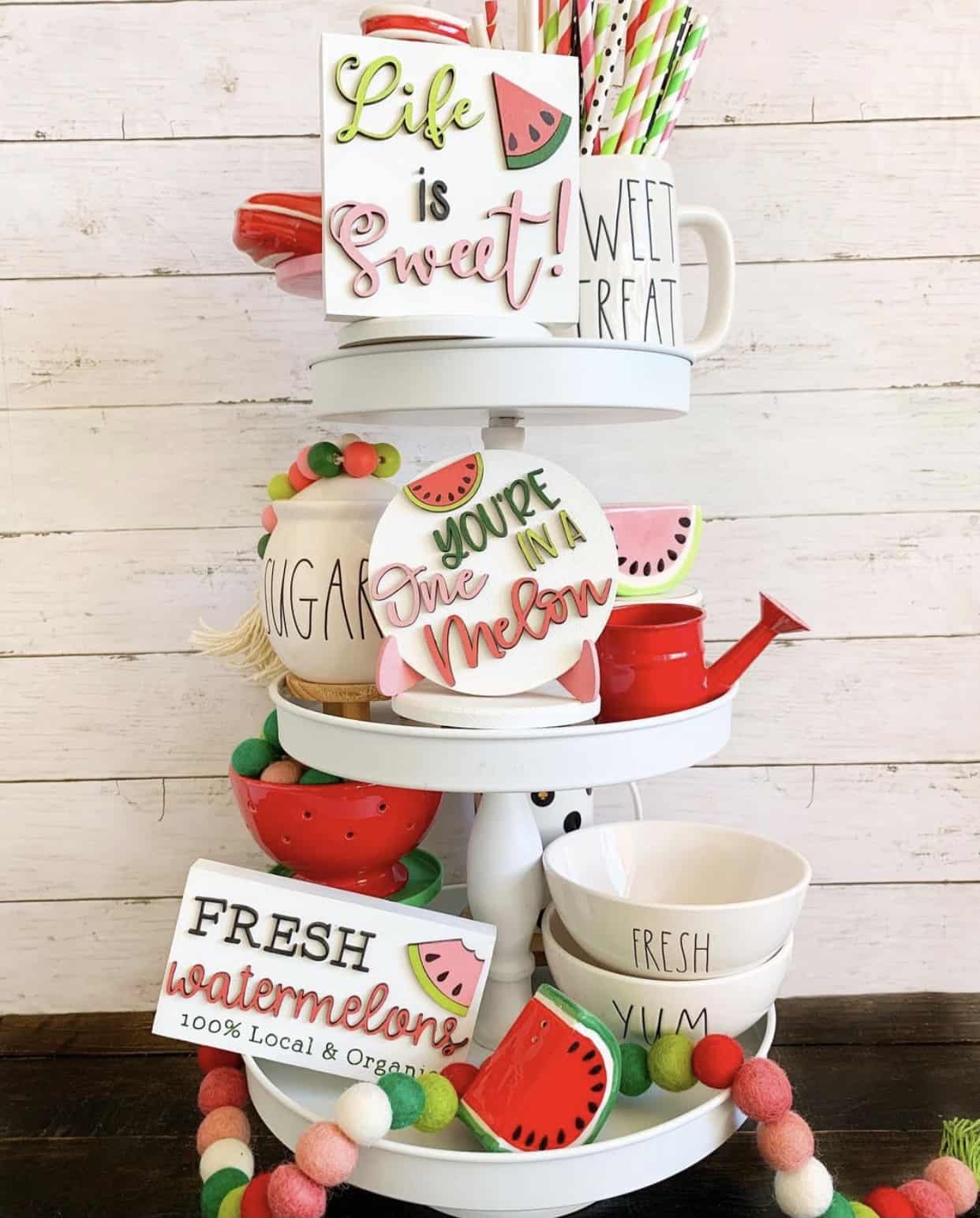 3-tiered classic white cupcake stand with white dishes, kitschy sayings, colorful straws and small watermelon figures.