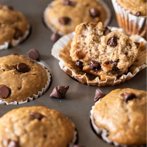 Banana Chocolate chip muffins in a muffin tin with one muffin broken open to show texture.